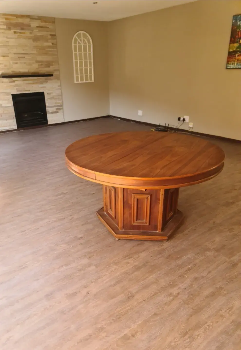 The same living room with a wood-look plank floor laid throughout and a round table in the middle.