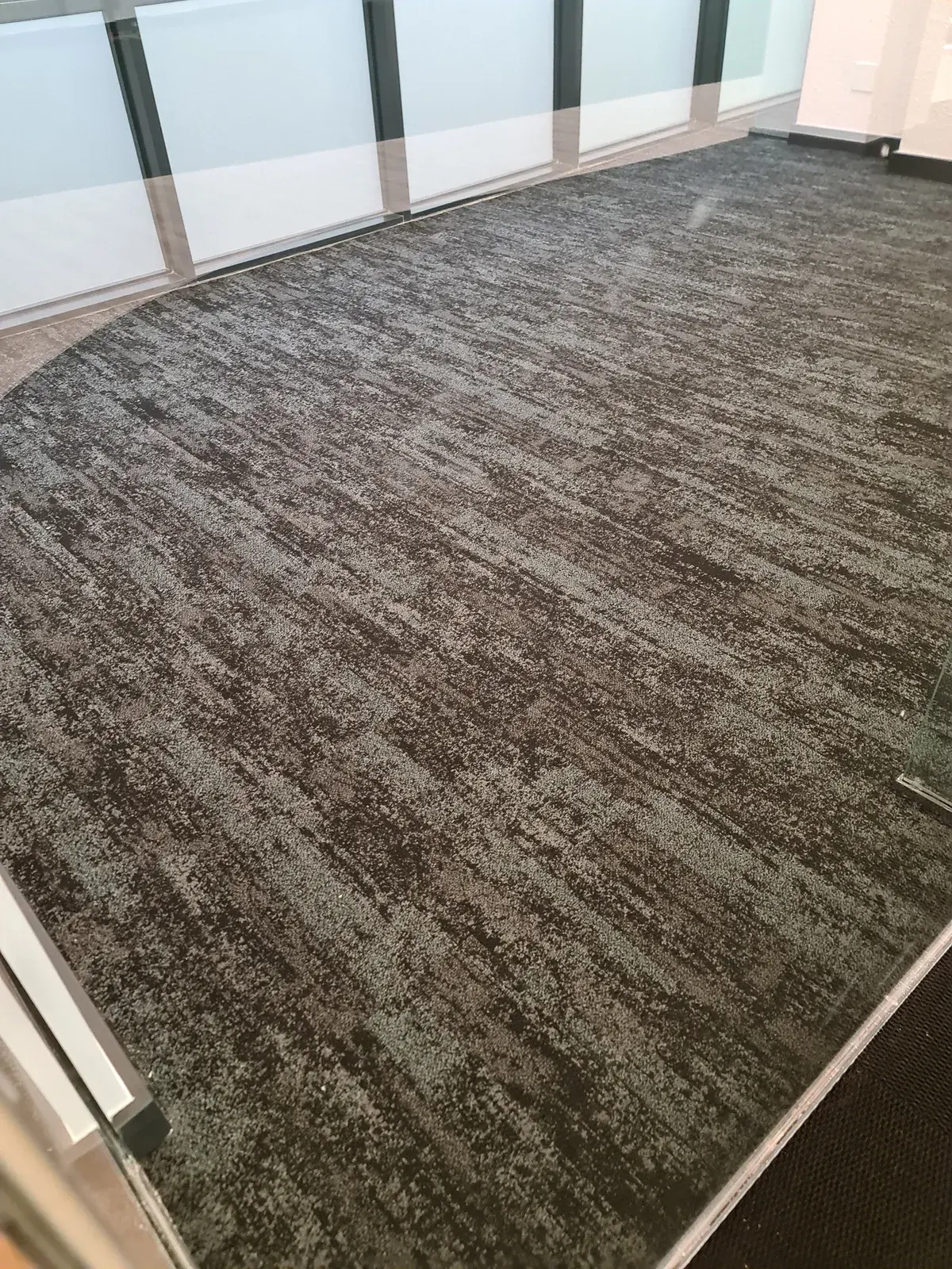 Charcoal and grey carpet in an office, cut to the curve of a glass wall.