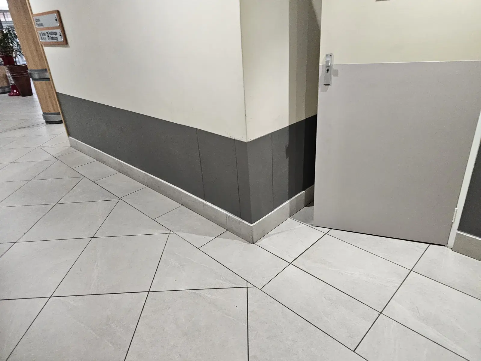 A hospital wall corner clad to dado height in dark grey protection sheets, beside a door with a grey protection sheet.
